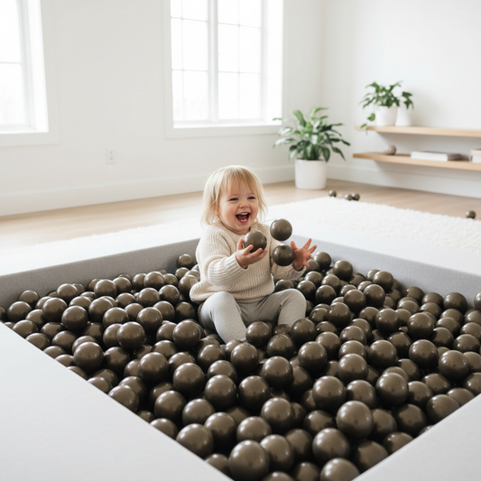 Kind in ballenbak met donker brons metallic ballen in lichte kamer